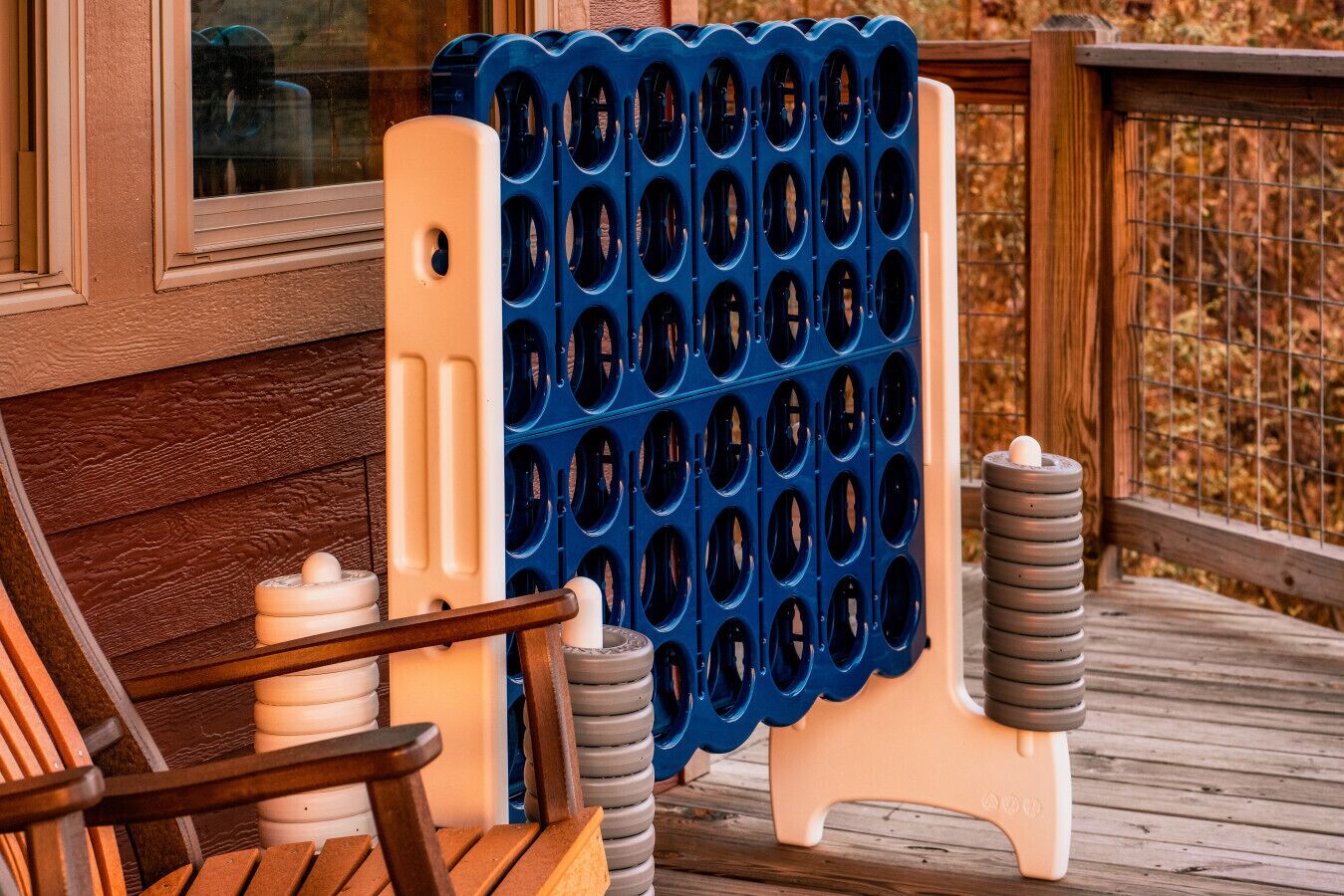 Ein Holzdeck mit einem blau-weißen Gesellschaftsspiel, einem Holzstuhl und einer Ansammlung weißer und grauer Gegenstände.
