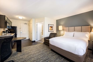 Ein Hotelzimmer mit Bett, Schreibtisch, Stuhl und einem Bild an der Wand.