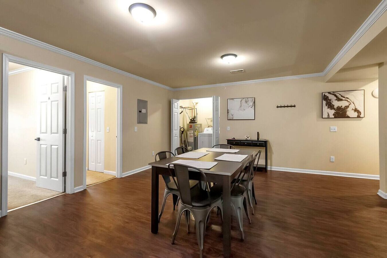 Un comedor amplio con una mesa larga y sillas, una cocina al fondo y un pasillo que conduce a otra habitación.
