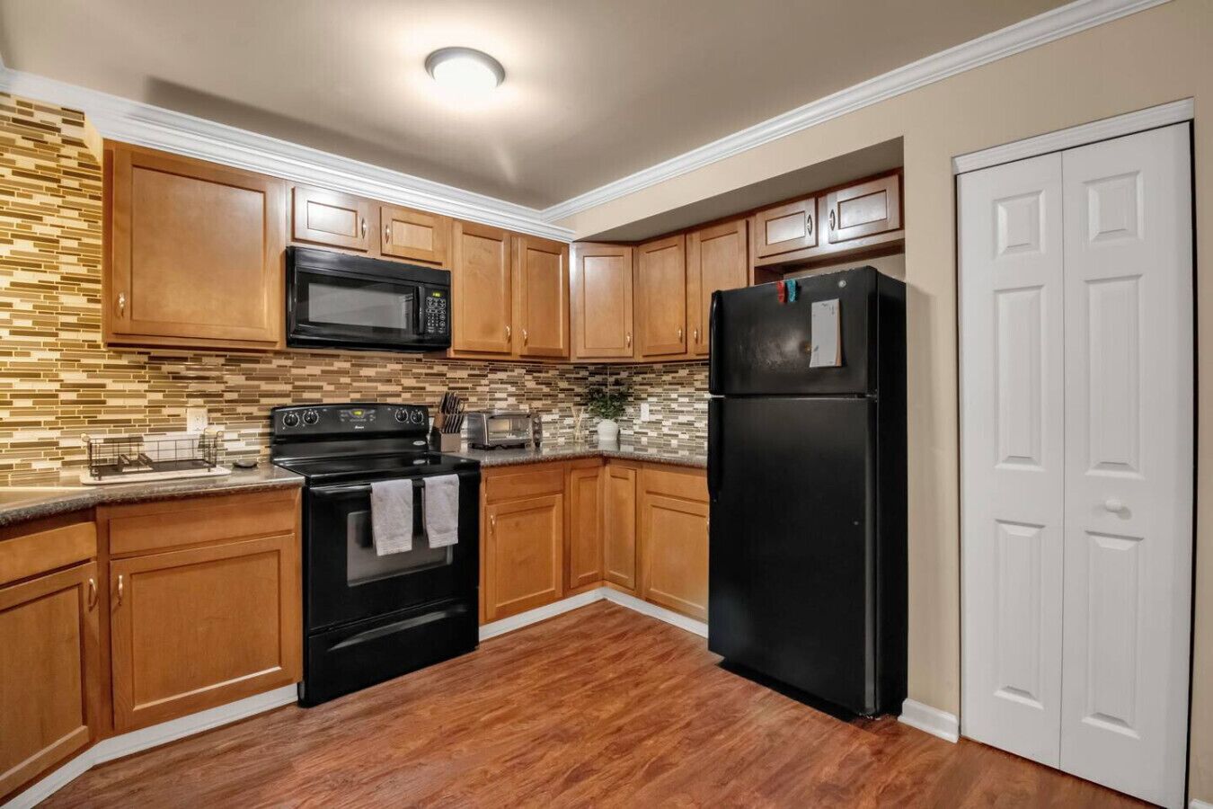 A kitchen with wooden cabinets, a black refrigerator, a black stove, and a microwave.