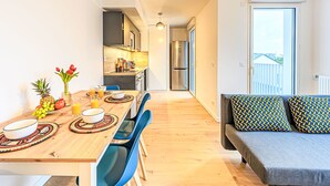 A modern kitchen with a dining area, a sofa with patterned cushions, and a view of the outdoors. - Ar Marine by Interhome (Quiberon)