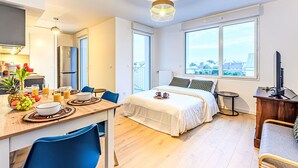 A modern hotel room with a dining area, a bed with a city view, and a television. - Ar Marine by Interhome (Quiberon)