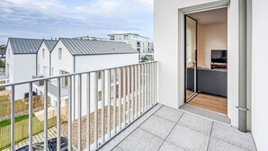 A balcony with a view of neighboring buildings, a door leading to a room with a TV, and a wooden pergola. - Ar Marine by Interhome (Quiberon)