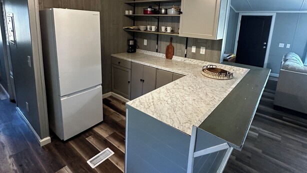 Una cocina moderna con refrigerador empotrado, encimera de mármol y piso de madera.