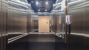 An interior view of a modern elevator with metallic walls and a control panel on the right. - Melo Alves 31 2p 1q (São Paulo)