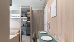A compact hotel room with a kitchenette, a dining area with a table set for two, and a bed in the corner. - Melo Alves 32 2p 1q (São Paulo)