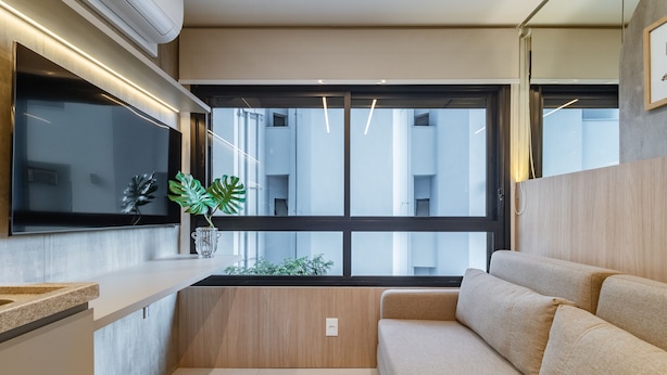 A modern kitchen with a built-in stove, a large window, and a beige sofa. - Melo Alves 32 2p 1q (São Paulo)
