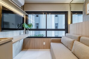 A modern kitchen with a built-in stove, a large window, and a beige sofa. - Melo Alves 32 2p 1q (São Paulo)