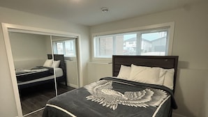 A bedroom with a bed, a closet, and a window. - RR Luxury Basement Suite, located in a peaceful and friendly neighborhood (Brandon)