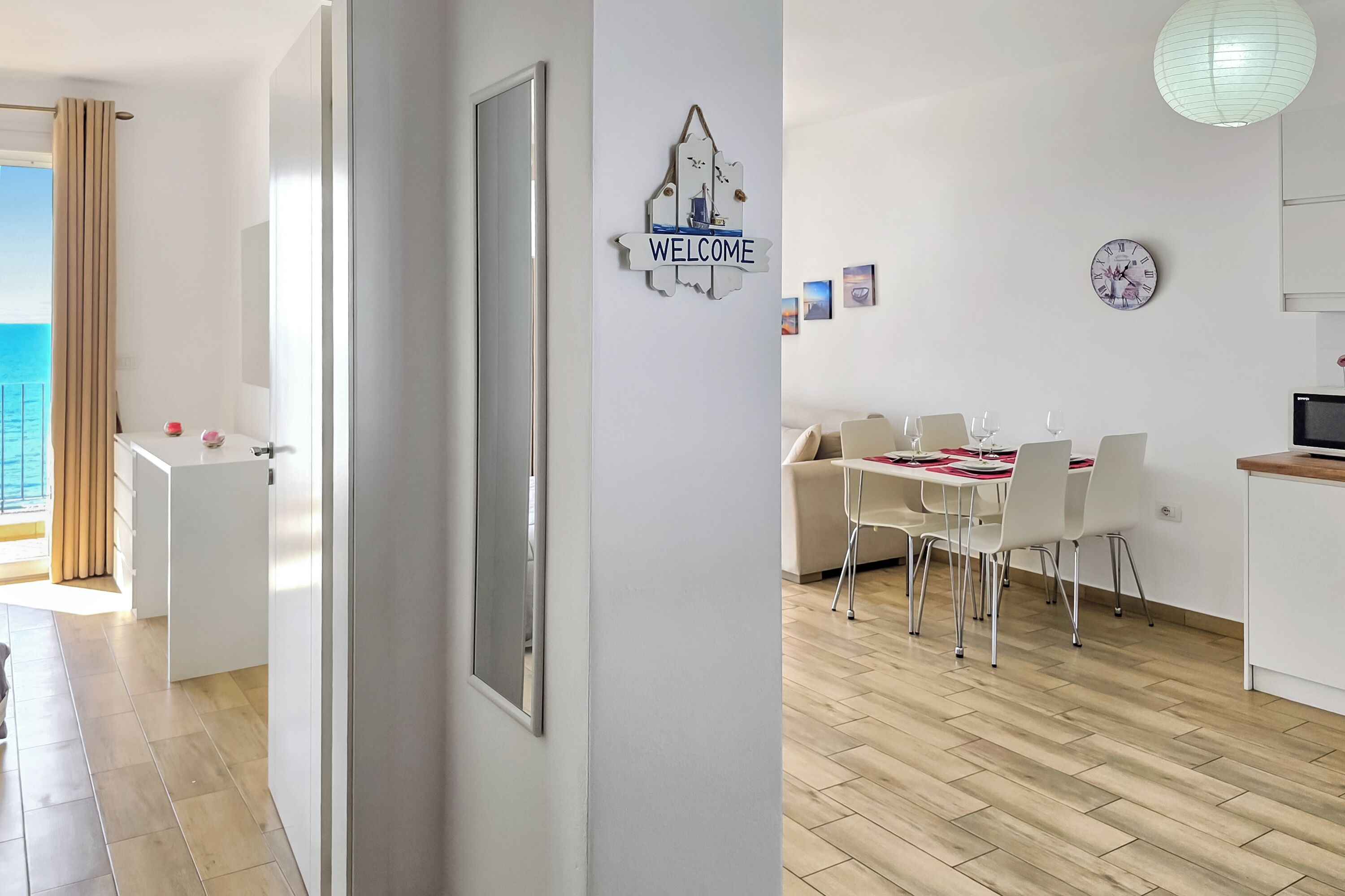 Una habitació d'hotel moderna amb vistes al mar, una zona de menjador amb taula per a dues persones i una cuina.