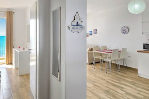 Ein moderner, gut beleuchteter Raum mit Essbereich, einer Küche und Blick aufs Meer.