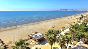 A beach with a small building, palm trees, and a clear view of the ocean. - Vista del Mare 120, Durres, Albania (Durres)