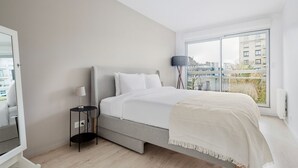 A modern bedroom with a bed, bedside table, lamp, and large window with a city view. - Blueground | Chaillot, city view, nr Eiffel Tower (Paris)