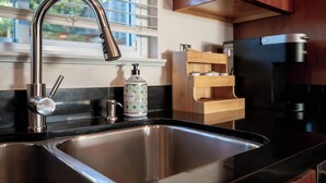 A kitchen with a stainless steel sink, a faucet, a canister, and a coffee maker.