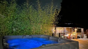 A hot tub in an outdoor setting with a bamboo fence in the background.