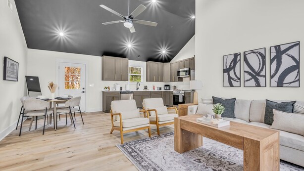 Un salon moderne avec une table basse en bois, un canapé et un coin repas avec des chaises.