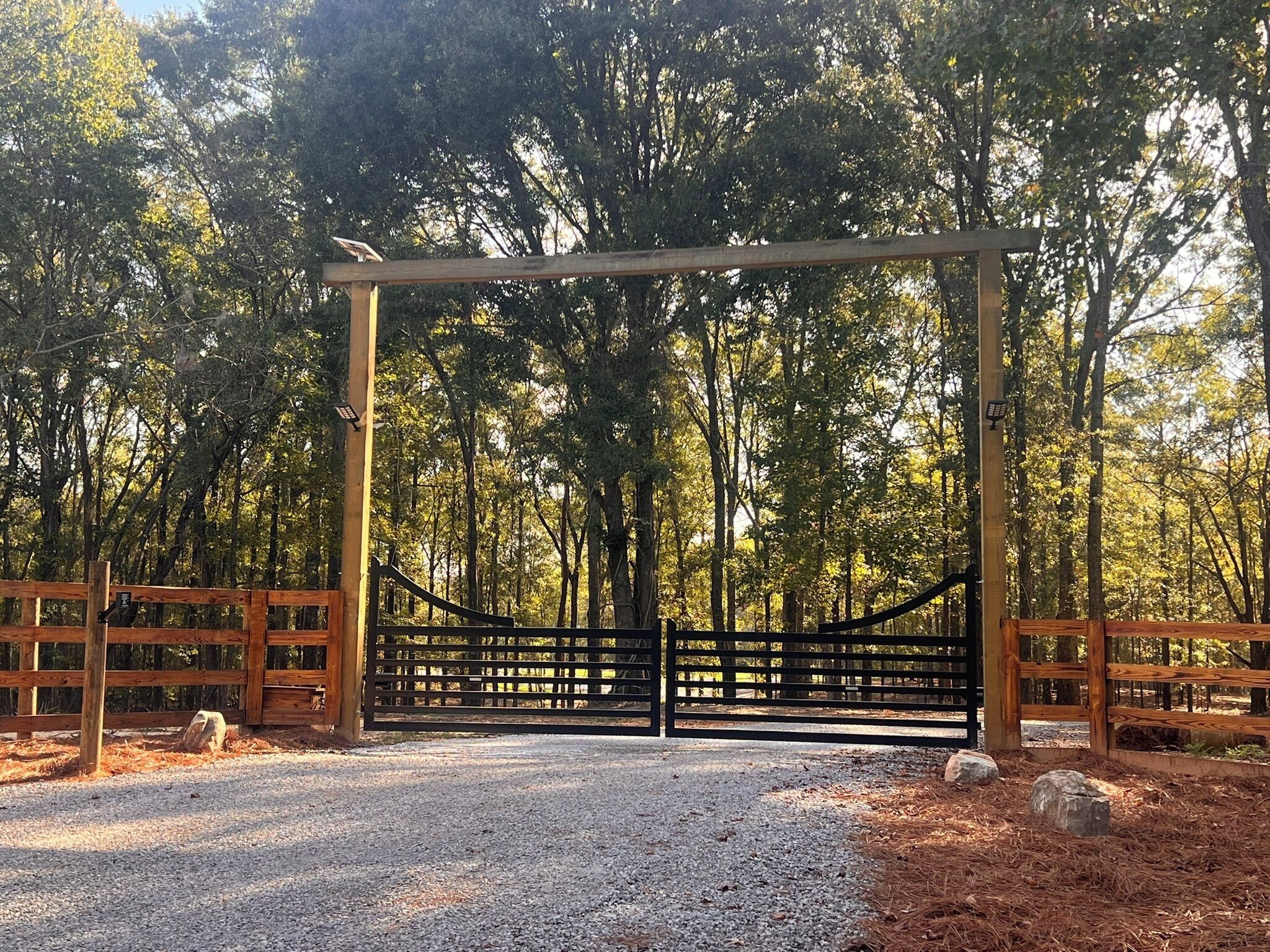 Een hekpoort naar een park, met een houten omheining en een metalen poort.