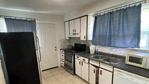 A compact kitchen with white cabinets, a black refrigerator, a microwave, and a dishwasher. - Cozy Home in North York Toronto (Toronto)