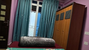 Un dormitorio con una cama, un armario de madera y una ventana con cortinas.