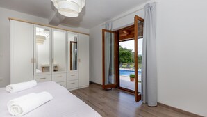 Quarto com cama, guarda-roupa, espelho e porta de vidro deslizante para varanda com vista para a piscina.