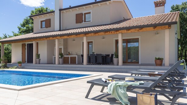 Uma casa moderna com piscina, área de estar externa e um alpendre coberto.