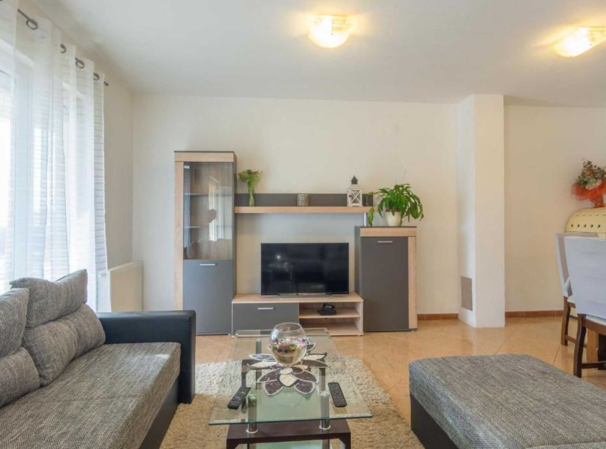 A modern living room with a sofa, coffee table, TV, and a small cabinet.