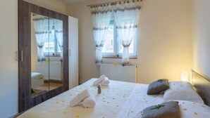 A bedroom with a large bed, a wardrobe, a window with curtains, and a radiator. - Holiday House Balen With Swimming Pool (Benkovac)