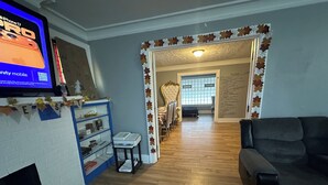 A living room with a TV, a fireplace, a bookshelf, and a dining area. - Fantastic 5-bedroom house with AC in charming Highland Park (Highland Park)