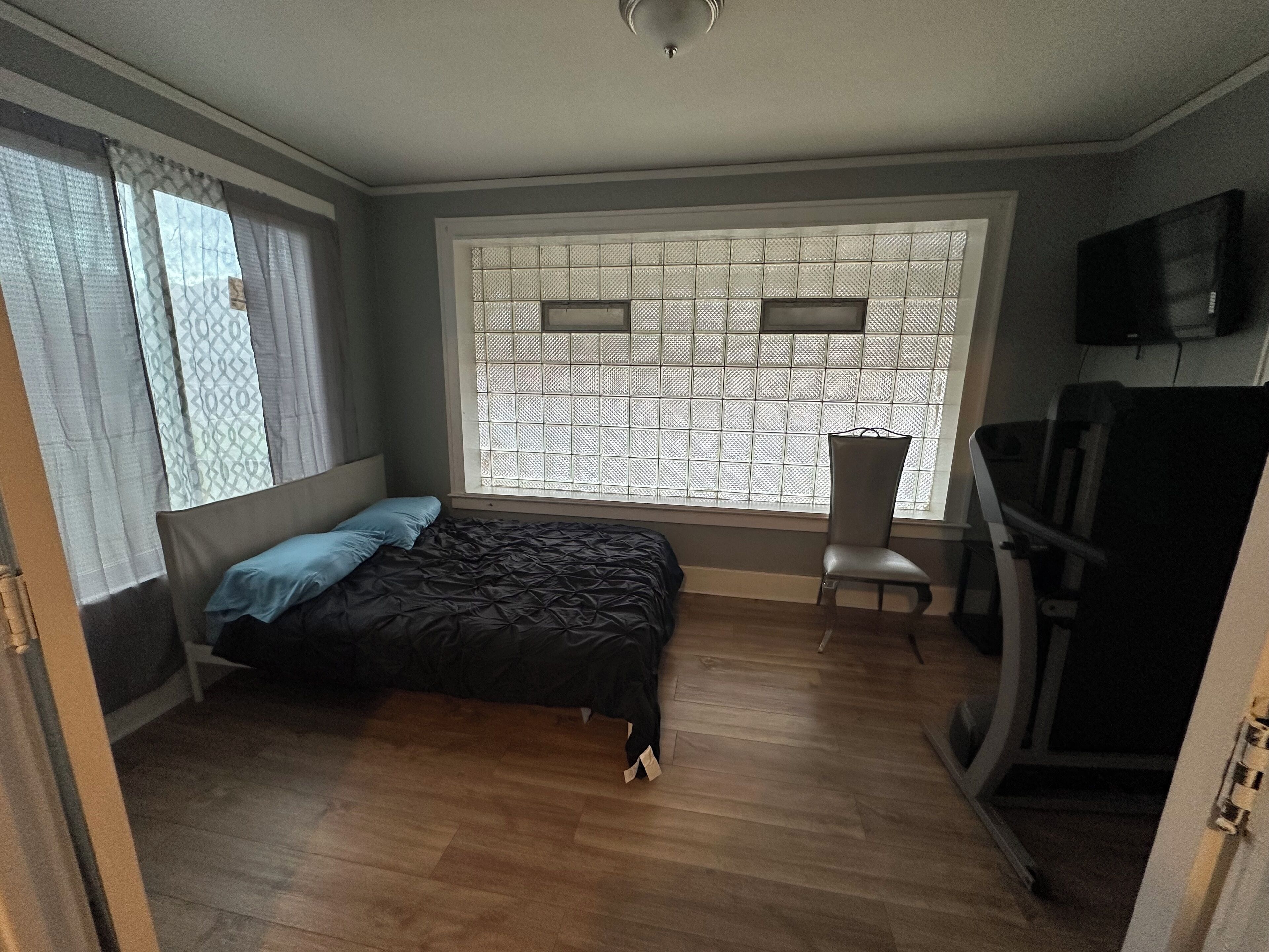 Una habitación con cama, una silla, un televisor y una ventana con vistas.