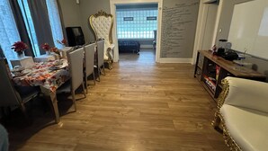 A dining area with a table set for four, a white upholstered chair, and a view into the kitchen. - Fantastic 5-bedroom house with AC in charming Highland Park (Highland Park)