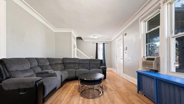 A living room with a sectional sofa, a round coffee table, and a blue bench by a large window. - Fantastic 5-bedroom house with AC in charming Highland Park (Highland Park)