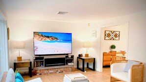 Una sala de estar moderna con televisor de pantalla plana, muebles de madera y una chimenea de ladrillo.