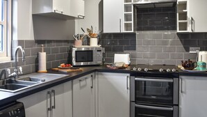Una cocina moderna con electrodomésticos de acero inoxidable, microondas, horno y lavaplatos.