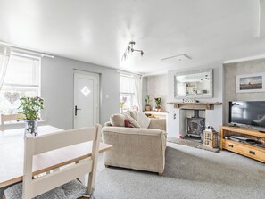 A living room with a sofa, TV, fireplace, and a dining area with a table and chairs.