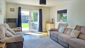 A living room with a sofa set, a television, a cabinet, and a view through a glass door. - 4 bedroom accommodation in California (California)