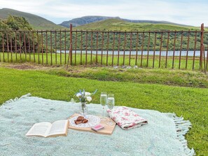 A picnic setup on a grassy area with a view of a lake and hills. - A traditional Welsh cottage beside Nantlle Lake in the stunning Nantlle Valley. (Nantlle, near Caernarfon)