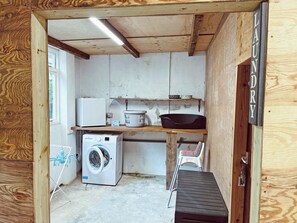Ett tvättrum med tvättmaskin, torktumlare och en hylla med en korg och en tallrik.