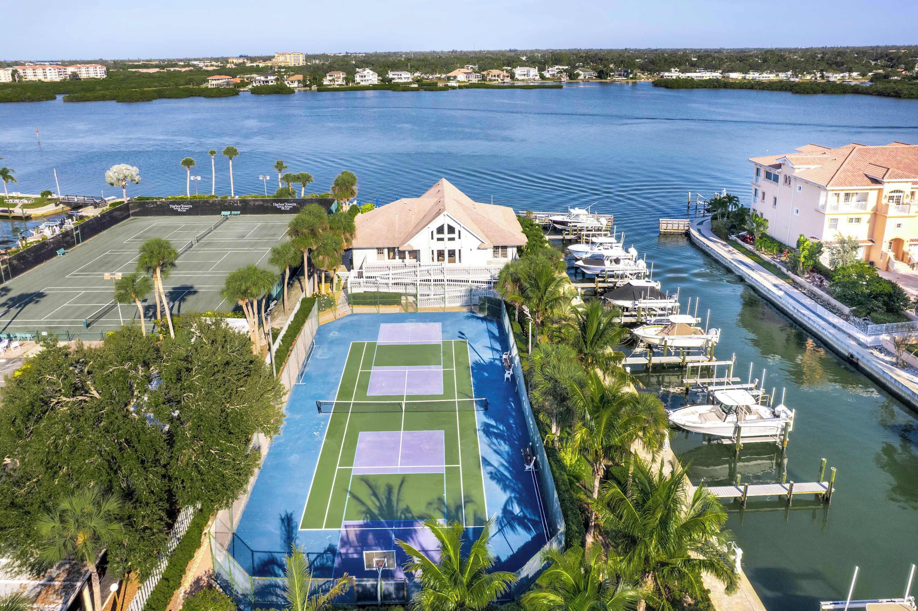 A tennis court adjacent to a marina with boats docked.