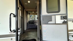 Interior de una caravana con zona de cocina, espacio para dormir y baño.