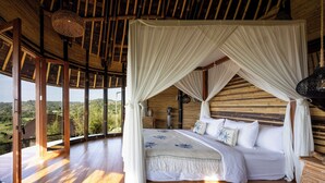 Una habitación amplia con una cama grande, piso de madera y vista al exterior.