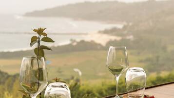 Mesa servida con copas de vino y una planta, con vistas a un paisaje pintoresco.