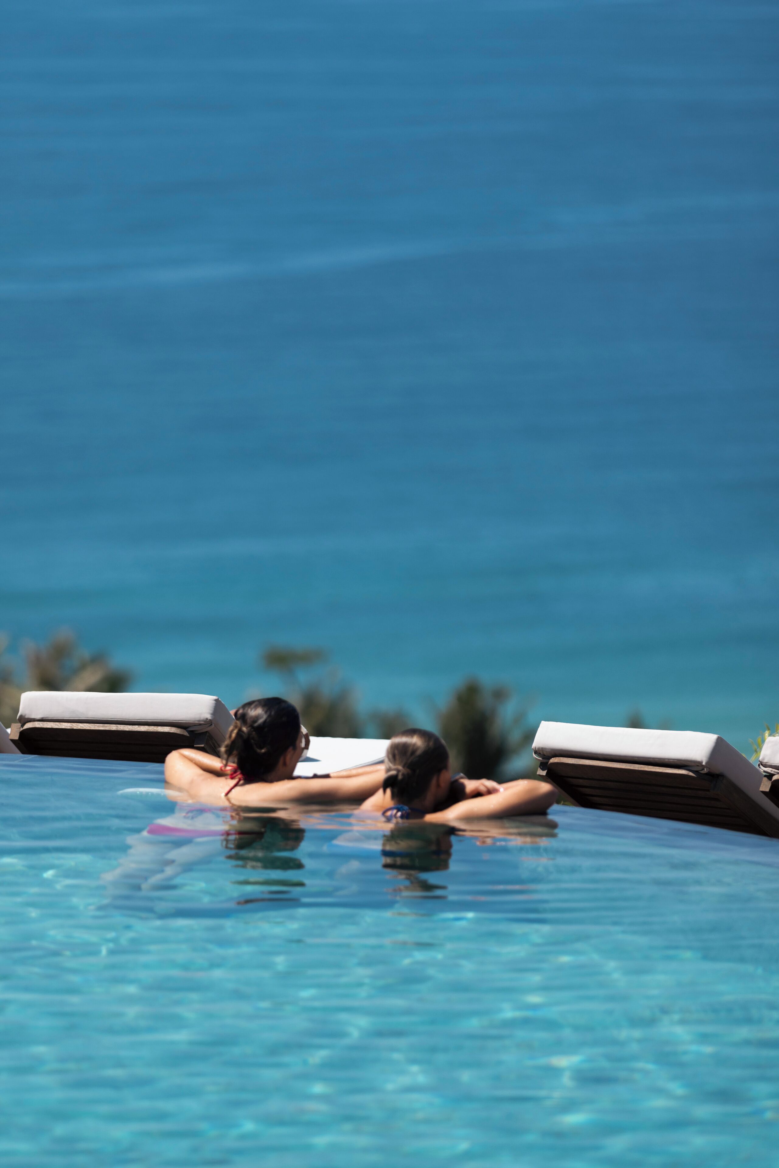 A poolside area with lounge chairs and a view of the ocean.