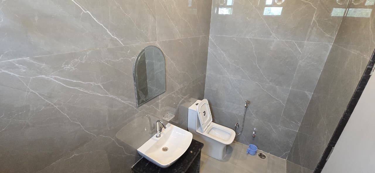 Ein Badezimmer mit Marmorboden, Waschbecken, Toilette und Spiegel.