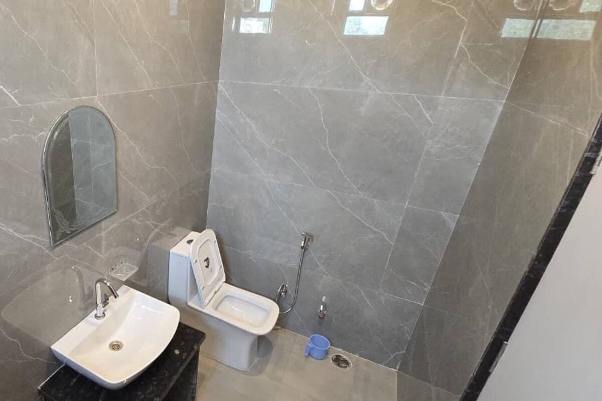 A bathroom with a marble floor, a sink, a toilet, and a mirror.