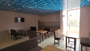 Una stanza con soffitto azzurro decorato, una TV a schermo piatto montata a parete e un angolo cottura con zoccolo piastrellato.