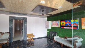 Una hall con soffitto in legno, un divisorio in vetro e due divani.