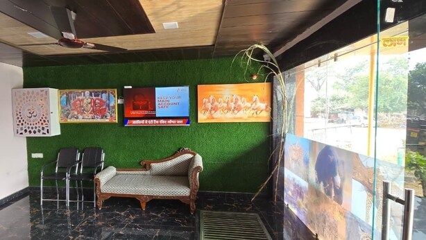 Una hall con un muro verde, una poltrona, due sedie, un mobile decorativo e un poster.
