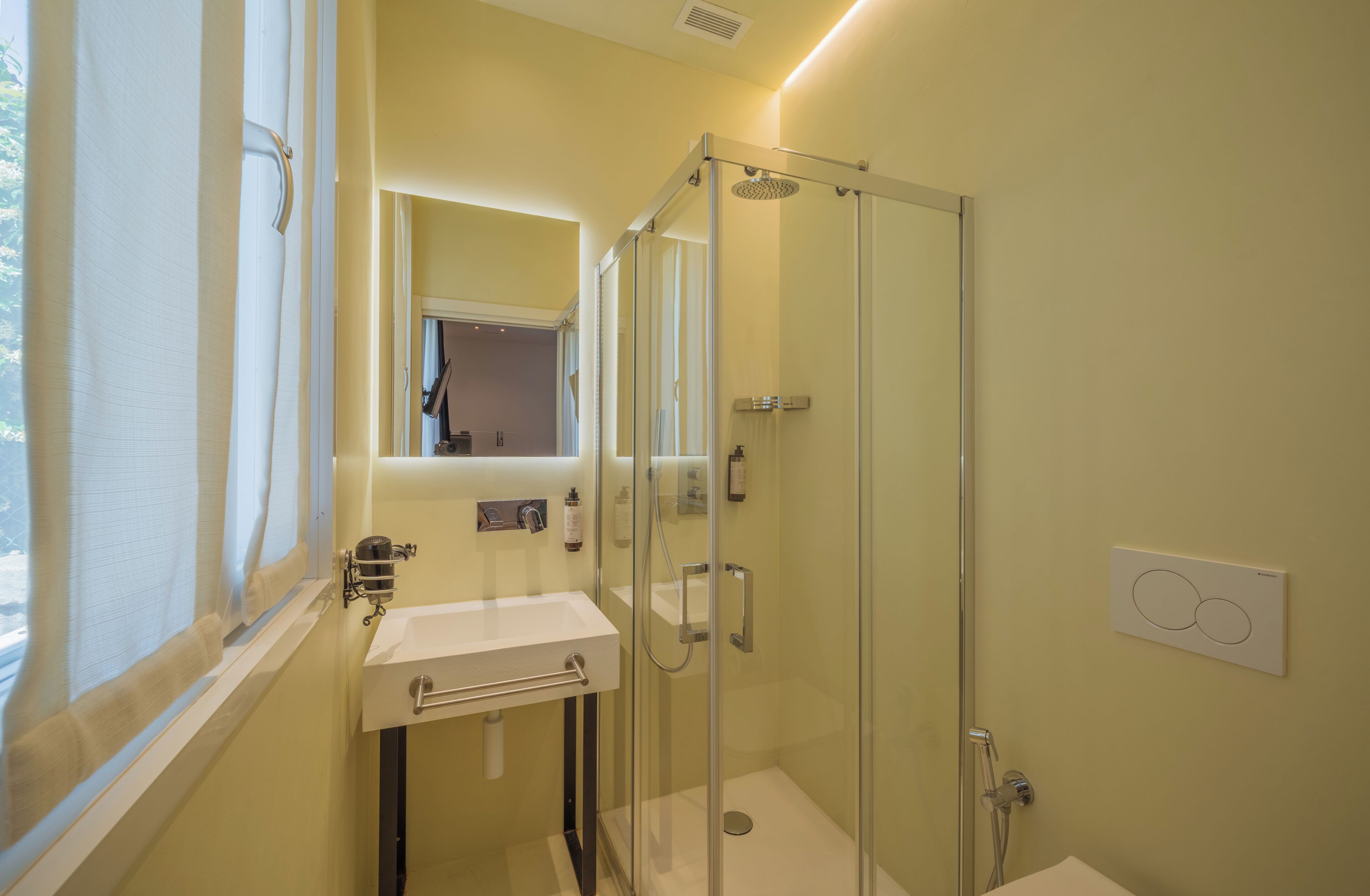 A bathroom with a glass-enclosed shower, a sink, and a mirror.