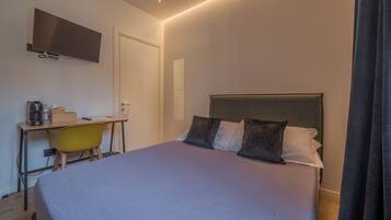 Une chambre à coucher avec un lit, un bureau, une chaise, une télévision et une porte.
