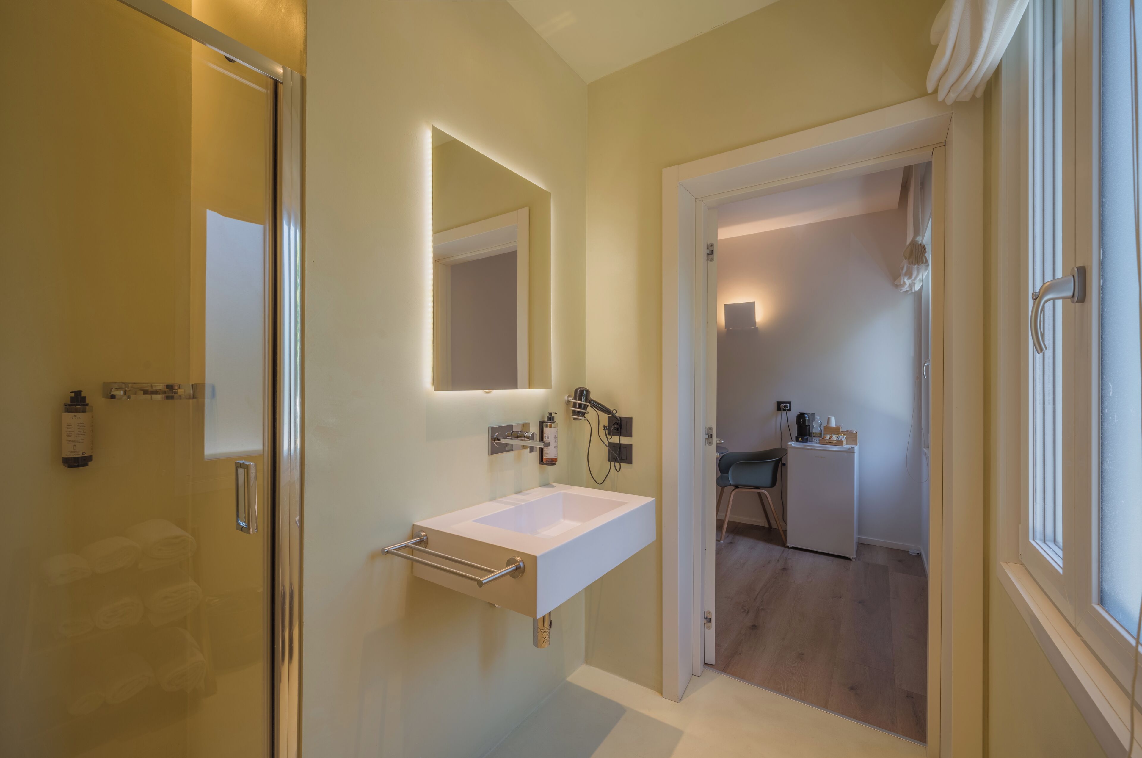 Un bagno moderno con cabina doccia in vetro, un lavandino bianco con specchio e una piccola angolo cottura.